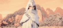 a woman in a white hooded cape covering her face