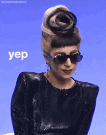 a woman wearing sunglasses and a bun with the word yep on it .