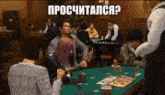 a group of people are playing poker in a casino and a man is holding a bottle of beer .