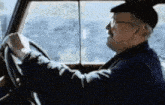 a man wearing glasses and a hat is driving a vehicle