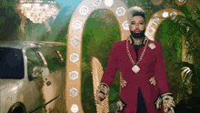 a man in a red coat and gold chains is standing in front of a limousine