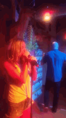 a woman singing into a microphone in front of a sign that says ' coca cola '