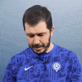 a man with a beard is wearing a blue shirt that says nike on it