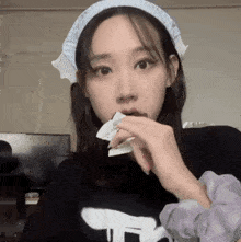 a woman wearing a headband and a purple scrunchie eating something