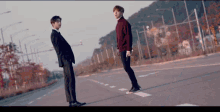a man in a suit and a man in a red sweater are standing next to each other on a street .