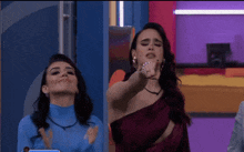 two women are standing next to each other on a stage and one of them is pointing .