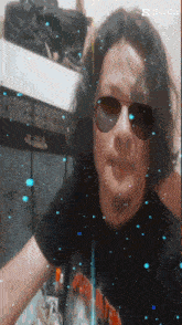 a man wearing sunglasses and a black shirt has a capcut watermark on the bottom right
