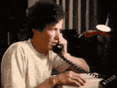 a man is sitting at a desk talking on a telephone .