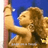 a woman is dancing in front of a wall and says `` baby im a thug '' .