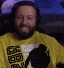 a man with a beard wearing headphones and a yellow shirt that says jbg on it