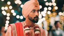 a man with a beard wearing a pink turban and a garland around his neck