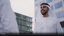 a man in a white robe is smiling in front of a building with shutterstock written on the bottom