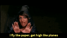 a woman in a hooded jacket is making a hand gesture with the words i fly like paper get high like planes below her