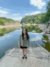 a woman stands on a dock near a lake