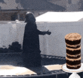 darth vader is standing on a trampoline next to a stack of cookies