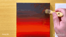 a person is painting a red and black gradient on a canvas with a brush