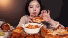 a woman is sitting at a table eating a sandwich and pizza .
