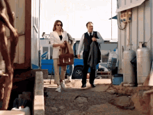 a man and a woman are walking down a dirt path