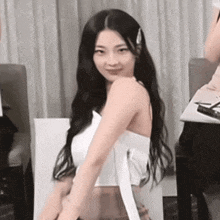 a woman with long hair is wearing a white top