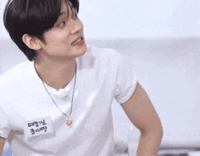a young man wearing a white t-shirt with a name tag that says ' a ' on it