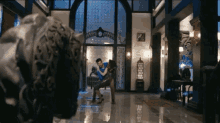 a man and woman are hugging in a room with a statue of a tiger in the background