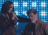 a woman is singing into a microphone next to a man