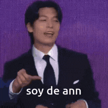 a man in a suit and tie is making a funny face and saying soy de ann .