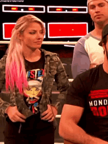a woman with pink hair is standing next to a man wearing a black shirt with the word mono on it