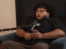 a man wearing glasses is sitting in front of a microphone with the number 20 on his shirt