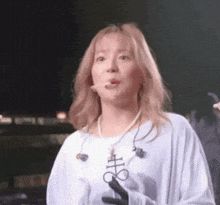 a woman wearing a white shirt and a pearl necklace is blowing a bubble .