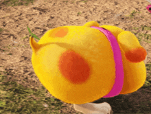 a yellow stuffed animal with a pink band around its neck