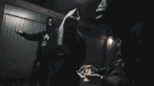 a person in a hooded jacket stands in a dark room