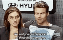 a man and a woman are talking to each other in front of a sign that says hyundai .