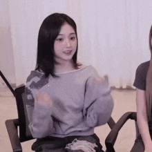 a woman in a gray sweater is sitting in a chair