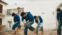 a man in a blue hoodie is dancing in front of a white building with a sign on it that says mexican culture