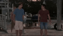 a group of young men are standing on a pier talking to each other