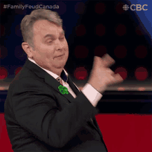 a man in a suit and tie with a clover pin on his lapel is giving a thumbs up sign