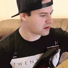 a man wearing a black shirt that says twenty on it is playing a guitar