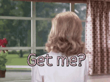 a woman standing in front of a window with the words " get me " written on her back