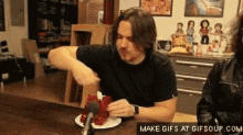 a man is sitting at a table eating a plate of food .
