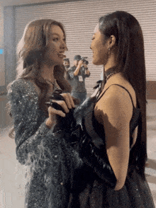 two women are standing next to each other in front of a cameraman