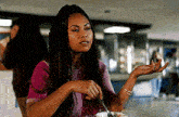 a woman with dreadlocks is sitting at a table eating food with a fork .