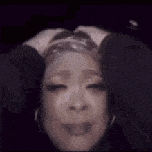 a close up of a woman 's face with her hands on her head and her eyes closed .