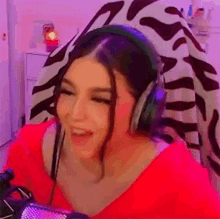 a woman wearing headphones is sitting in front of a microphone in a room .