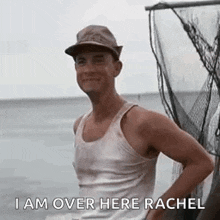 a man wearing a hat and a tank top is standing next to a fishing net in the water .