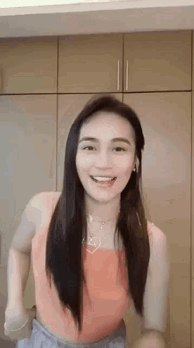 a woman in a pink tank top is dancing in a room .