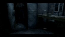a man is walking through a dark room with a desk in the foreground