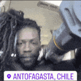 a man with dreadlocks is standing next to another man with dreadlocks and a sign that says antofagasta chile