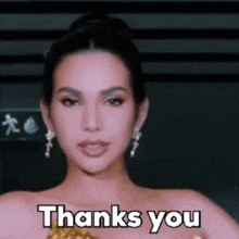 a woman wearing earrings and a bun says thanks you