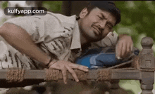 a man is laying on a wooden bed with his hands on his back .